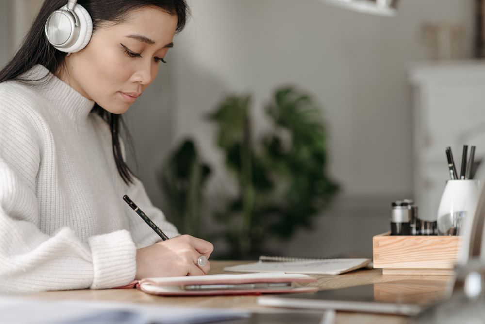 A student studying with headphones and taking notes