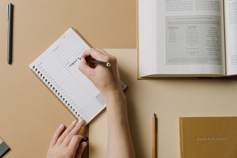 A hand writing a schedule in a planner